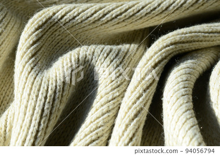 Fabric texture of a soft yellow knitted sweater. Macro image of the structure of bindings in yarns Fabric texture of a soft yellow knitted sweater. Macro image of the structure of bindings in yarns 94056794