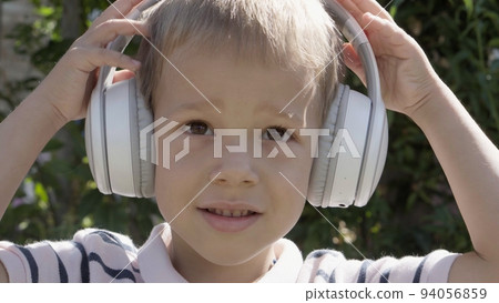 Portrait of Cute Little Boy With Headphones Listening to Music. Cheerful Carefree Childhood. Preschool Girl Feeling Free and Funky, Good Emotions Life. Child Listening to Music in Home and Dancing 94056859