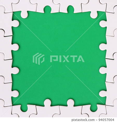 Framing in the form of a rectangle, made of a white jigsaw puzzle around the green space Framing in the form of a rectangle, made of a white jigsaw puzzle around the green space 94057004