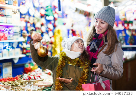Woman and her daughter are preparing for Christmas and choosing balls on the tree 94057123