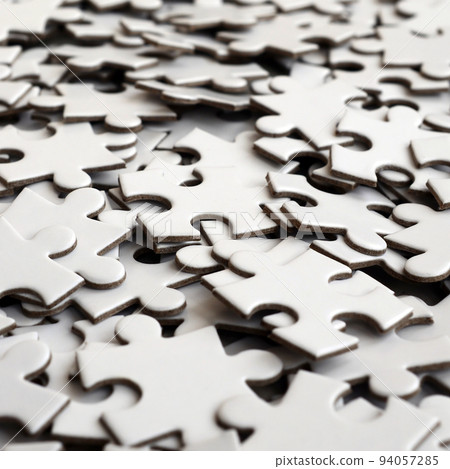 Close-up of a pile of uncompleted elements of a white puzzle. A huge number of rectangular pieces from one large white mosaic 94057285