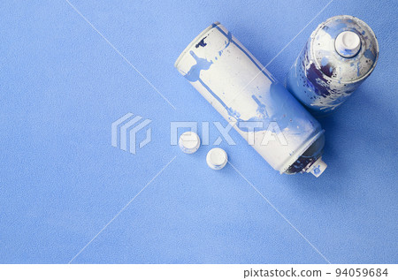 Some used blue aerosol spray cans and nozzles with paint drips lies on a blanket of soft and furry light blue fleece fabric. Classic female design color. Graffiti hooliganism concept Some used blue aerosol spray cans and nozzles with paint drips lies on a blanket of soft and furry light blue fleece fabric. Classic female design color. Graffiti hooliganism concept 94059684