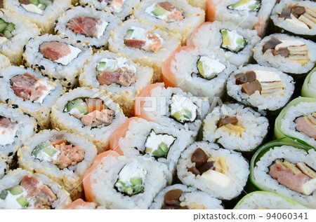 Close-up of a lot of sushi rolls with different fillings. Macro shot of cooked classic Japanese food. Background image Close-up of a lot of sushi rolls with different fillings. Macro shot of cooked classic Japanese food. Background image 94060341