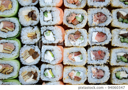 Close-up of a lot of sushi rolls with different fillings. Macro shot of cooked classic Japanese food. Background image Close-up of a lot of sushi rolls with different fillings. Macro shot of cooked classic Japanese food. Background image 94060347