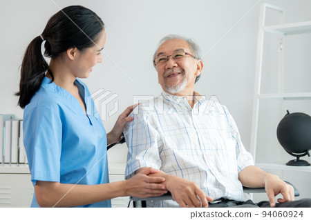 Happy positive asian nurse giving support and touching contented senior man. 94060924