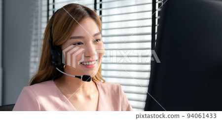 Competent female operator working on computer and while talking with clients. 94061433