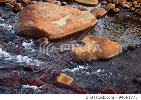 Brown stones coloring the flow of the Zao River 94061775