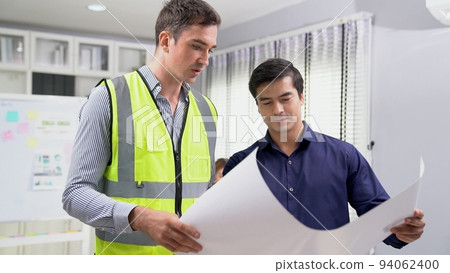 Competent investor investor discuss and brainstorm with engineers on blueprint. 94062400