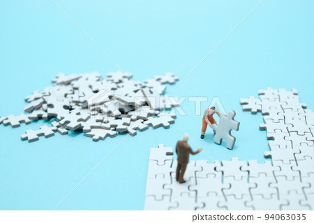 一個在淺藍色背景上組裝白色拼圖的工人和一個講道的辦公室工作人員的形象 94063035