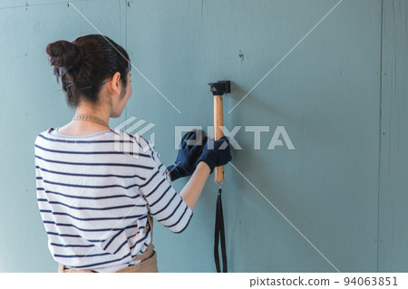 Japanese woman driving a nail in the garage (renovation/DIY) 94063851
