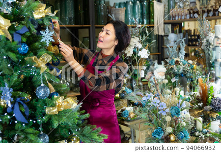 Woman salesman decorates christmas tree in flower shop 94066932