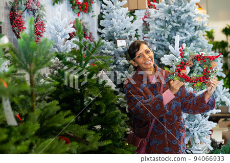 Woman buying New Year decor at flower shop Woman buying New Year decor at flower shop 94066933