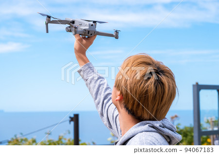 Young man enjoying drone photography outdoors in sunny weather 94067183