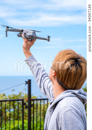 Young man enjoying drone photography outdoors in sunny weather 94067186