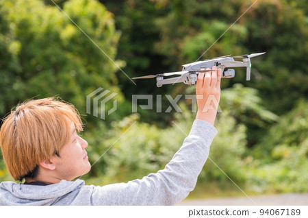 Young man enjoying drone photography outdoors in sunny weather 94067189