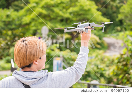Young man enjoying drone photography outdoors in sunny weather 94067190