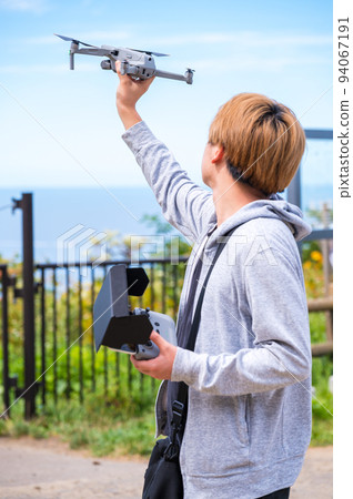 在陽光明媚的天氣裡享受戶外無人機攝影的年輕人 94067191