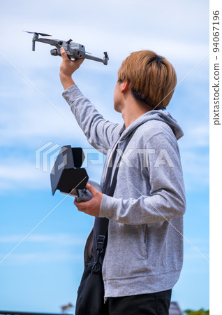 Young man enjoying drone photography outdoors in sunny weather 94067196