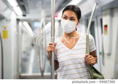 Woman in face mask standing in subway train Woman in face mask standing in subway train 94067360