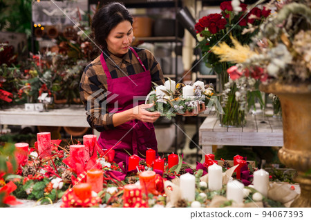 Store employee makes Christmas composition with candles 94067393