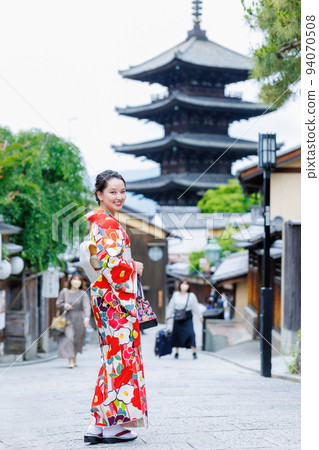 A young woman in a kimono standing with a five-storied pagoda in the background 94070508