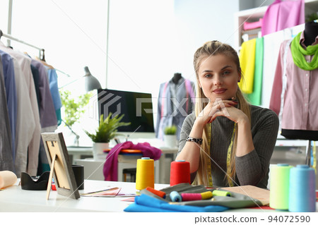 Portrait of smiling young dressmaker or tailor sewing fabric creates new clothes in own workshop 94072590