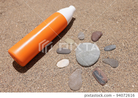 Sun made of stones on sea sand orange liquid bottle of cream or lotion Sun made of stones on sea sand orange liquid bottle of cream or lotion 94072616