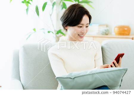 A woman watching a smartphone on the sofa 94074427