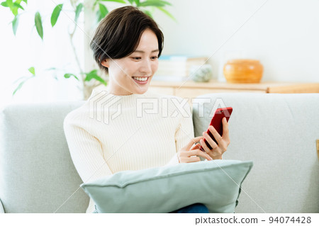 A woman watching a smartphone on the sofa A woman watching a smartphone on the sofa 94074428