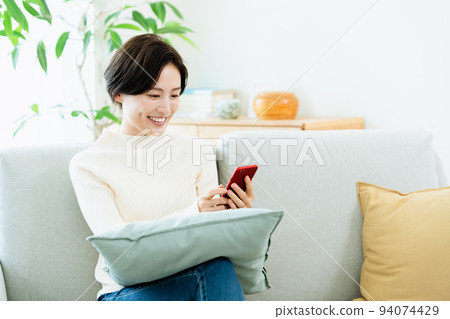 A woman watching a smartphone on the sofa 94074429