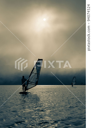 windsurfer silhouette on sunset background windsurfer silhouette on sunset background 94074524