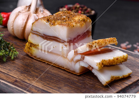 Smoked lard, bacon, half a piece, on a wooden dark cutting board Smoked lard, bacon, half a piece, on a wooden dark cutting board 94074779
