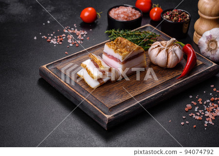 Smoked lard, bacon, half a piece, on a wooden dark cutting board Smoked lard, bacon, half a piece, on a wooden dark cutting board 94074792