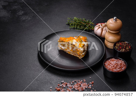 Delicious fresh liver cake with mayonnaise and carrots on a black plate against a dark concrete background 94074857