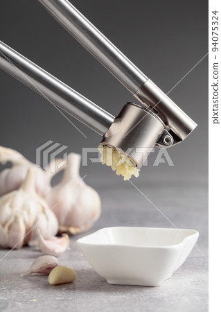 Squeeze the garlic with a garlic press. 94075324