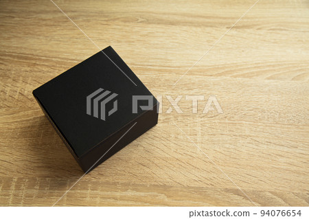 Closed rectangular cardboard box with corrugated cardboard lid, on oak wooden table 94076654