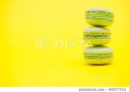 Delicious stack of green macaroons over yellow background. Luxury dessert Delicious stack of green macaroons over yellow background. Luxury dessert 94077316