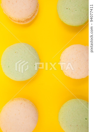 Peach and green tee macaroons in rows over yellow background. Luxury dessert Peach and green tee macaroons in rows over yellow background. Luxury dessert 94077411
