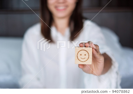 Happy Woman holding smile emotion face block. Customer choose Emoticon for user reviews. Service rating, mental health, positive thinking, satisfaction, evaluation and feedback concept Happy Woman holding smile emotion face block. Customer choose Emoticon for user reviews. Service rating, mental health, positive thinking, satisfaction, evaluation and feedback concept 94078862