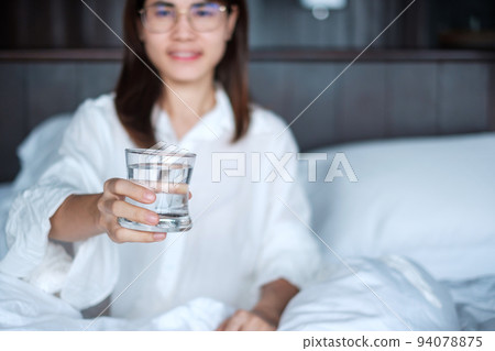 Happy woman holding water glass, female drinking pure water on bed at home. Healthy, Refreshment, lifestyle concept Happy woman holding water glass, female drinking pure water on bed at home. Healthy, Refreshment, lifestyle concept 94078875