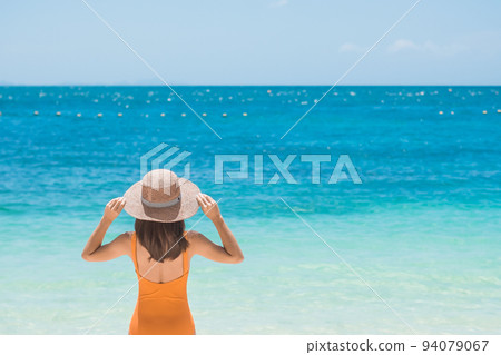 Woman tourist in orange swimsuit and hat, happy traveler sunbathing at Paradise beach on Islands. destination, wanderlust, Asia Travel, tropical summer, vacation and holiday concept 94079067