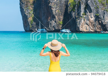 Woman tourist in yellow swimsuit and hat, happy traveller sunbathing at Maya Bay beach on Phi Phi island, Krabi, Thailand. landmark, destination Southeast Asia Travel, vacation and holiday concept 94079418