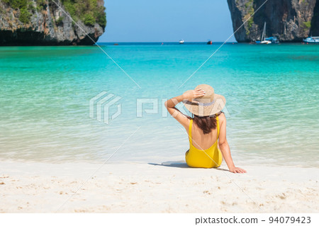 Woman tourist in yellow swimsuit and hat, happy traveller sunbathing at Maya Bay beach on Phi Phi island, Krabi, Thailand. landmark, destination Southeast Asia Travel, vacation and holiday concept 94079423