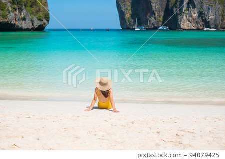 Woman tourist in yellow swimsuit and hat, happy traveller sunbathing at Maya Bay beach on Phi Phi island, Krabi, Thailand. landmark, destination Southeast Asia Travel, vacation and holiday concept 94079425