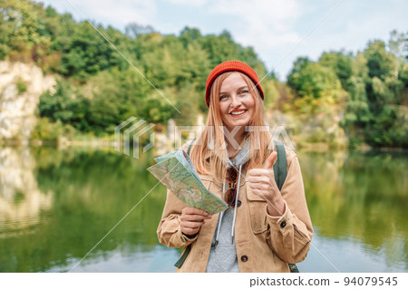 Traveling Happy woman with backpack shows like, looking at the camera and topographic map in green forests. Hiking adventure summer holiday concept. Traveling Happy woman with backpack shows like, looking at the camera and topographic map in green forests. Hiking adventure summer holiday concept. 94079545