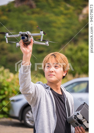 在陽光明媚的天氣裡享受戶外無人機攝影的年輕人 94079673