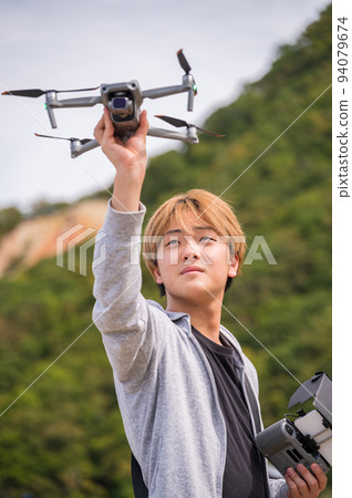 在陽光明媚的天氣裡享受戶外無人機攝影的年輕人 94079674