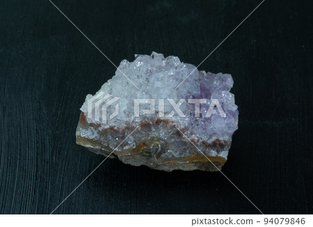 Amethyst violet variety of quartz from Brazil. Natural mineral stone on black background. Mineralogy, geology, magic of stones, semi-precious stones and samples of minerals. Close-up macro photo. 94079846