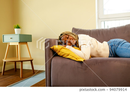 tired latin hispanic woman taking nap on the sofa during the day 94079914
