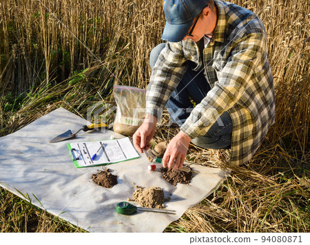 Agronomist preparing soil samples for laboratory analysis outdoors 94080871